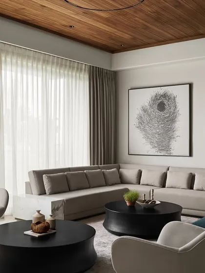 This view highlights the harmony between the furniture pieces. The custom L-shaped sofa, the twin "Orbit" coffee tables, and the "Pivot" armchairs are all arranged to create a conversational and relaxing living area filled with natural light.