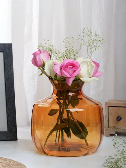 An amber glass vase with pink and white roses, shot in natural light. The soft, romantic lighting is perfect for showcasing delicate home decor items.