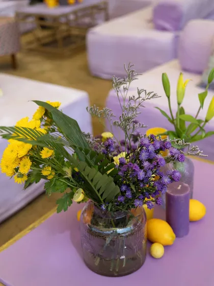 A centerpiece detail, combining yellow lilies, purple asters, and fresh lemons in a glass vase, perfectly capturing the theme.