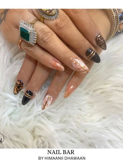 An elegant and bold set combining black, glitter, and white marble nails with gold stripe accents.