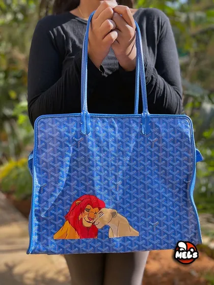 We take luxury to the next level by personalizing it. Here’s a classic blue Goyard tote bag we hand-painted with a timeless scene of Simba and Nala from The Lion King, turning a high-end accessory into a unique piece of Disney fan art.