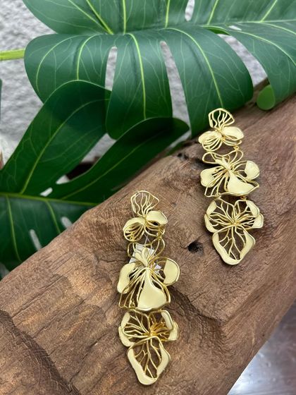A cascade of golden flowers. These long, dangling earrings are crafted with intricate cut-out floral motifs for a dramatic and feminine statement.