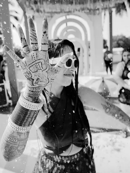 A fun, candid black and white shot of the bride showing off her intricate henna design during a pool party. We capture the playful moments that happen throughout the wedding festivities.