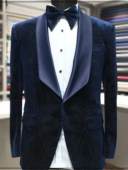 A navy blue velvet tuxedo with a subtle geometric pattern woven into the fabric. The wide satin lapels give it a classic, sophisticated feel.