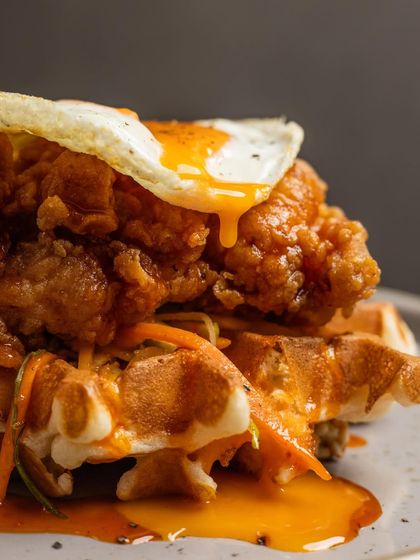 A close-up shot capturing the textures of our Fried Chicken and Waffles, from the crispy coating on the chicken to the pockets of the waffle.