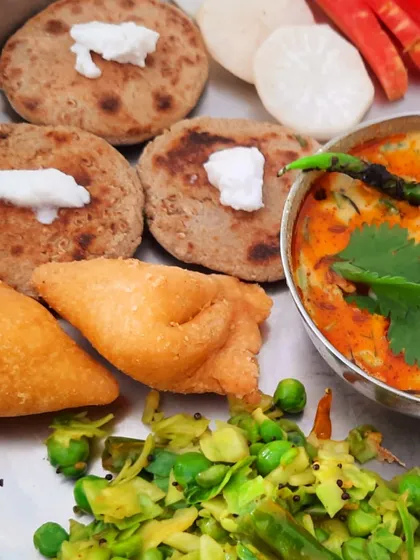 A close-up of the bajra rotis topped with my vegan ghee, served with mini samosas and a cabbage and pea stir-fry. This is the kind of soulful, everyday food I love to teach.