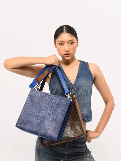 The Mini Porto, where design meets functionality. This versatile bag comes with both shoulder and crossbody strap options and is seen here in blue and brown.