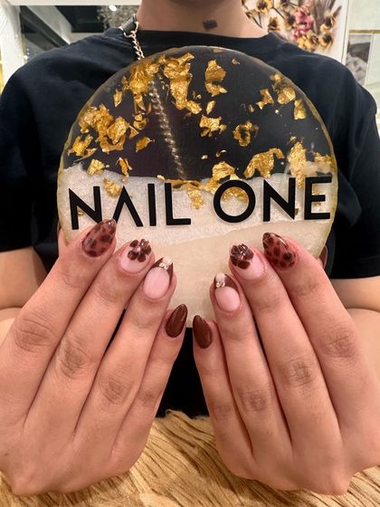 A full view of the almond-shaped nails featuring a mix of solid brown, leopard print, and floral accent nails. This set demonstrates how we can combine multiple trends into one cohesive and stylish manicure.