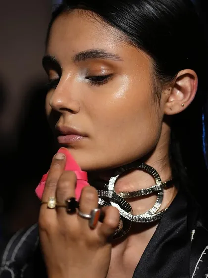 Using a makeup sponge to perfect the base, our artist ensures a smooth, glowing complexion for the model before she walks the ramp.