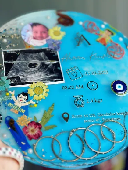 A closer look at the details in this 11-inch circular baby keepsake. You can see the sonogram, baby photo, birth stats, and other personal mementos like rakhis and silver kadas.