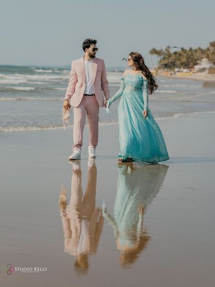 A stunning reflection shot on the wet sands of a Goa beach. The couple's reflection is almost perfectly mirrored, creating a beautiful and artistic pre-wedding photograph.