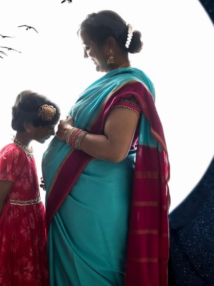 A mother and daughter sharing a quiet moment in silhouette. The moon backdrop adds a magical element to this sweet maternity photo.
