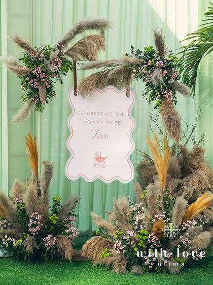 The welcome sign for the baby shower, framed by soft pampas grass.