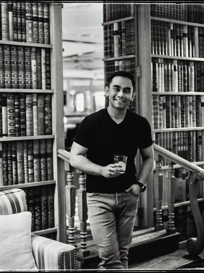 Kunal in a library, surrounded by books. The setting adds a sense of character and history to this classic black and white portrait.