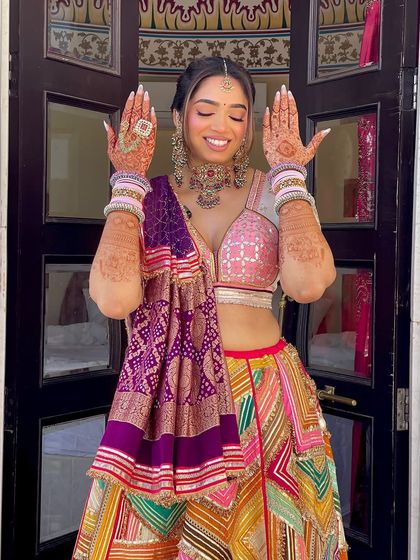 A happy bride showing off her Mehndi look. The intricate braid with the heavy accessory at the back is the star of her hairstyle.