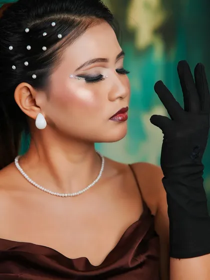 A profile view of the high-fashion look, emphasizing the clean lines and the elegant placement of the pearl accessories.