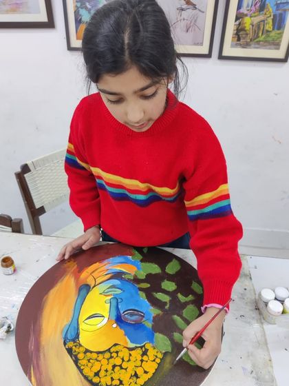 Multiple students are seen working on their own interpretations of Buddha paintings, showcasing a calm and focused studio environment.
