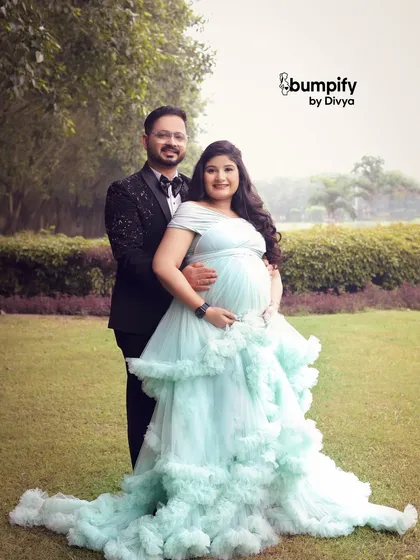 A happy and classic portrait of the couple in the park. Her beautiful light blue gown stands out against the green lawn, making for a stunning maternity photograph.