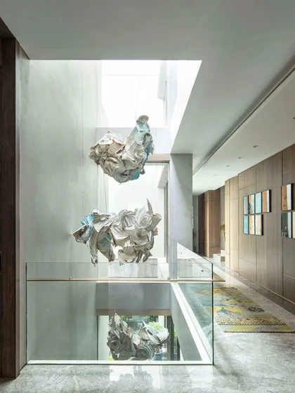 A view of the 'Radha Krishna Raas Leela' installation in the Bammi Residence, showing how the sculptural forms float within the skylit atrium. The piece is a modern interpretation of a divine story, crafted through Shibori and origami techniques.