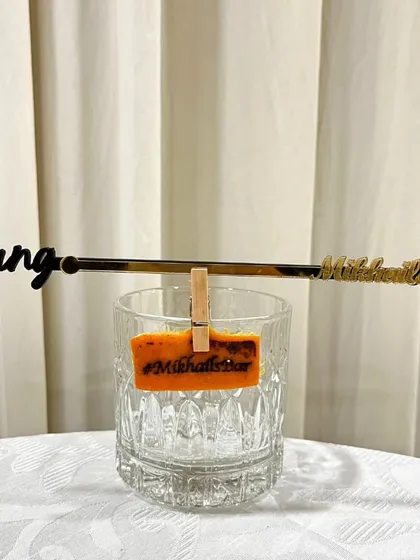 The complete personalized set: a custom stirrer and a heat-stamped garnish, both featuring the event's hashtag, #MikhailsBar.