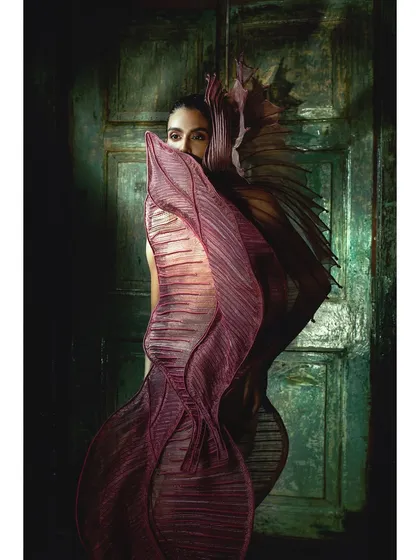 The model peers out from behind the flowing, architectural lines of a Vaishali S. creation. This image plays with concealment and revelation, a common theme in my high-fashion work.