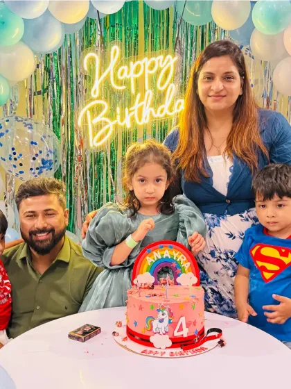 A family with their two sons, one dressed as Superman, at a unicorn-themed party. It's all about fun and making the kids happy.