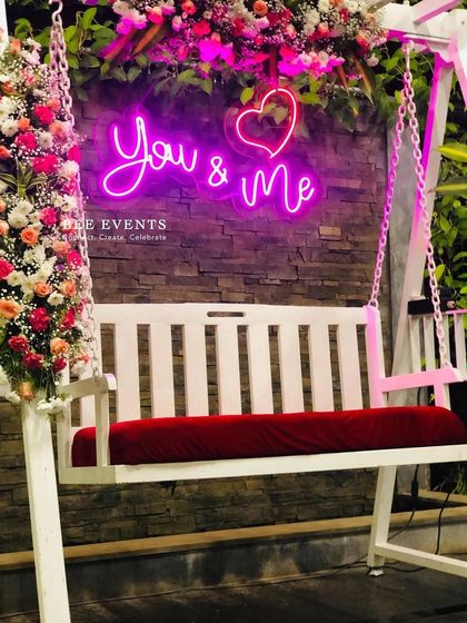 Another look at our popular floral swing photo booth. The combination of lush flowers, the warm glow of the neon sign, and the rustic brick background creates a charming and romantic spot for couples.
