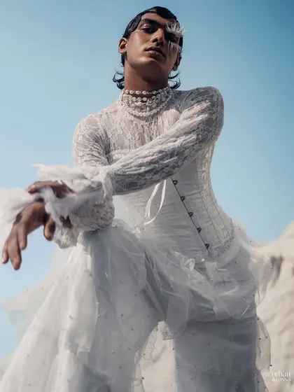 A powerful low-angle shot where the feather makeup and wet-look hair contribute to a commanding, high-fashion presence.