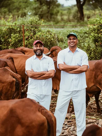 A portrait of the founders of Two Brothers Organic Farms, standing proudly among their herd of cows. This shot establishes the identity and vision behind the brand.