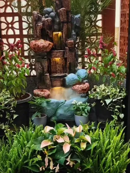 A compact, custom water feature designed for a small courtyard. The setup includes a small waterfall, integrated mist maker, and surrounding pockets for planting ferns and other moisture-loving plants.