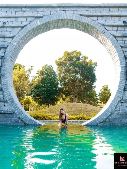 Using architecture to frame the subject, this poolside portrait captures a model in the water, seen through a large circular stone structure. It shows how I use the environment to create unique compositions in outdoor photography.