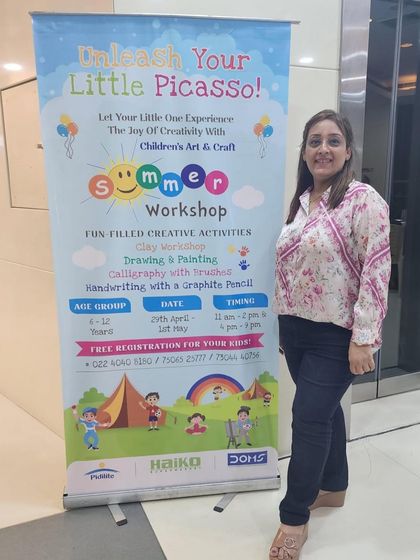 Here I am next to the banner for our "Unleash Your Little Picasso" summer workshop at Haiko Mall. These events are a fantastic way to bring art to the community in a fun and accessible setting.