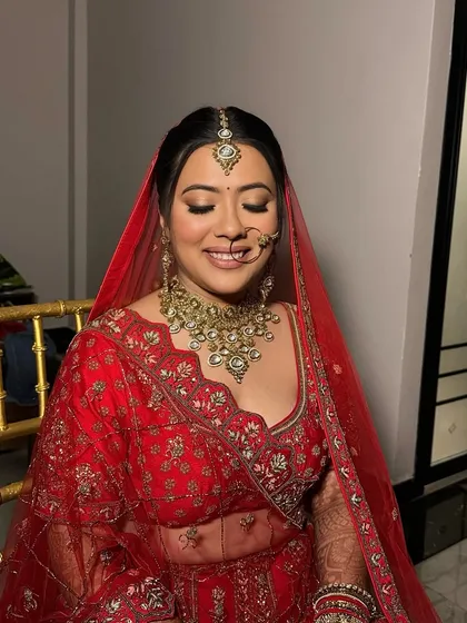 The smile of a happy bride is everything. Akansha's red bridal look was completed with soft golden eyes and a flawless base, making her glow on her special day.