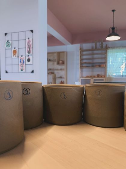 A line of our custom-stamped pots, with the studio's creative chaos in the background.