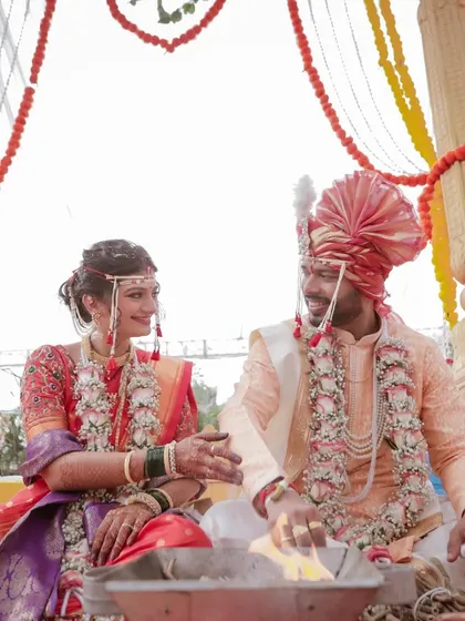 A candid moment during a Maharashtrian wedding ceremony. The bride and groom share a smile, seated at the holy fire, their connection evident even during the rituals.