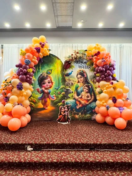 A Seemantha Sanskar ceremony setup with a backdrop featuring baby Krishna and Yashoda. The decor is brought to life with a colorful balloon arch in shades of orange, peach, and purple, perfectly complementing the artwork.