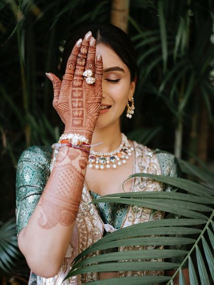 A classic Mehendi pose. This shot beautifully showcases the intricate henna design and the bride's soft, glowing makeup. The focus is on clean skin and subtly defined eyes, letting her natural beauty shine.