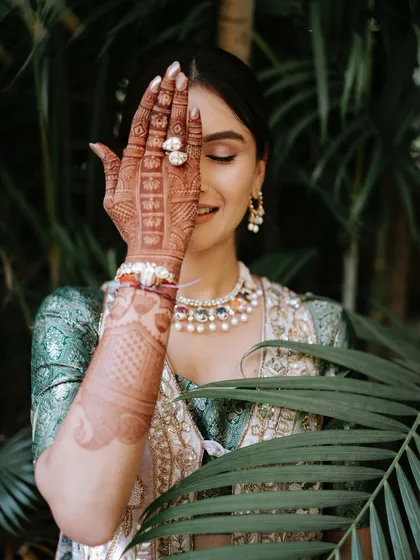 A classic Mehendi pose. This shot beautifully showcases the intricate henna design and the bride's soft, glowing makeup. The focus is on clean skin and subtly defined eyes, letting her natural beauty shine.