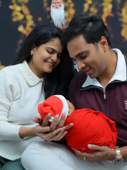 A beautiful family portrait for the holidays. Both parents smile as they hold their newborn baby, creating a cherished memory of their first Christmas together as a family of three.