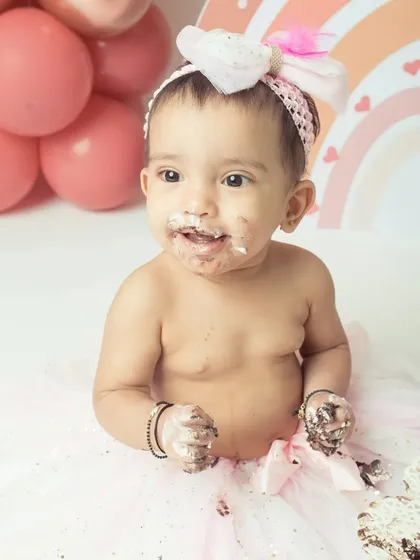 A sweet, cake-covered smile from the birthday girl. The aftermath of the cake smash is often the cutest part.