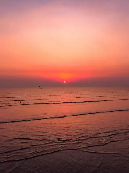 The sun, partially eclipsed, sets over the ocean, creating a shape that resembles Pac-Man.