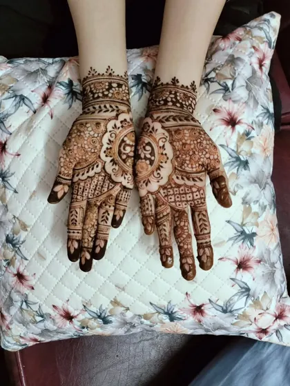 A classic, full-coverage party henna design. Both hands are adorned with matching central mandalas surrounded by dense, traditional patterns that cover the palms and fingers completely.