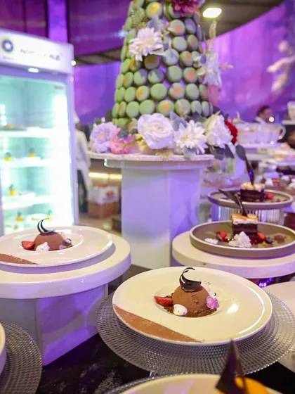 A dessert station featuring a beautiful macaron tower adorned with fresh flowers, alongside individually plated chocolate mousses.
