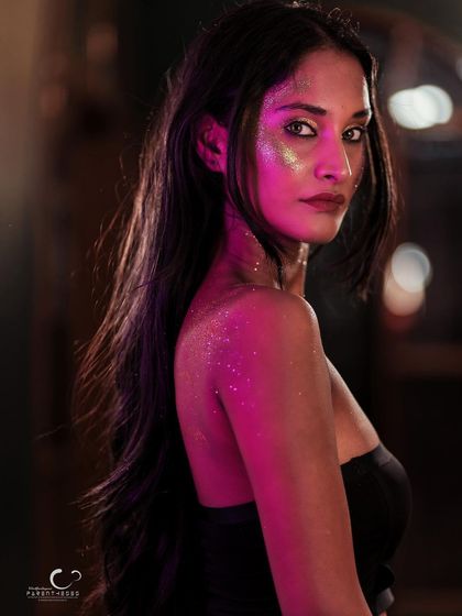 A dramatic and moody portrait. The pink light on her back and her intense gaze create a cinematic and captivating image.