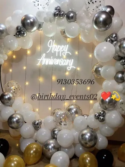 A sophisticated and elegant anniversary backdrop. This setup features a mix of white, silver, and confetti-filled balloons on a circular frame, with a delicate "Happy Anniversary" neon sign providing a beautiful focal point.