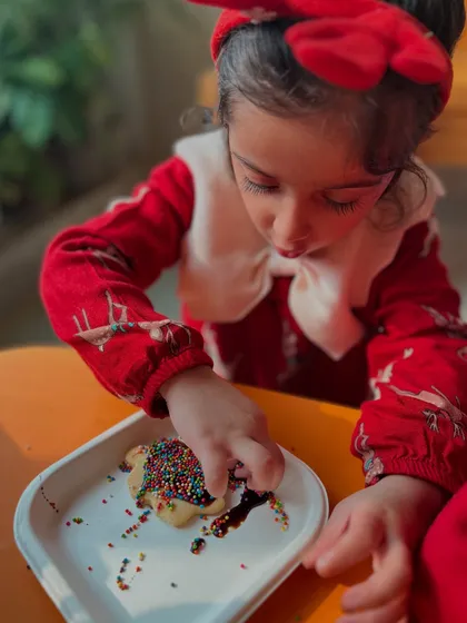 Sprinkles everywhere! A girl has fun adding the final touches to her cookie.