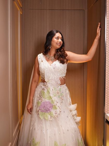 A full length pose showing the complete engagement look, from the soft curls to the beautiful lehenga.