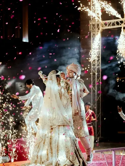 A high-energy shot of the couple on stage, surrounded by sparklers and celebrating their union.