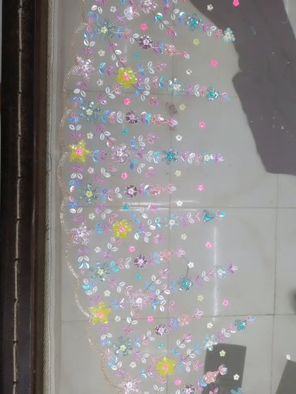 This detailed shot showcases the scalloped border and scattered floral motifs of a custom hand-embroidered piece. This kind of delicate work can elevate any outfit, from a lehenga to a dupatta.