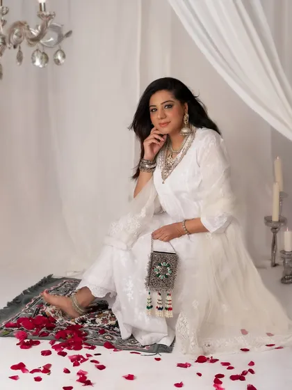 Beautiful in white. This portrait has a dreamy, ethereal quality, with the sheer curtains and scattered rose petals adding to the romantic and serene mood.